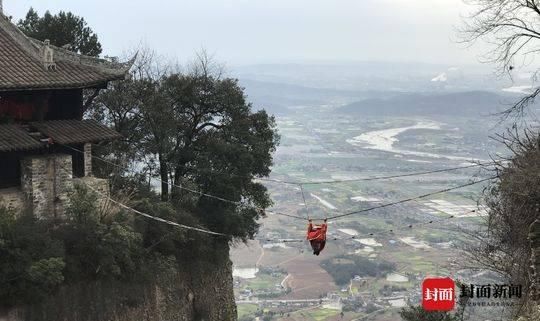 山峰绝壁铁索相连 七旬老人索上表演“倒挂金钩”